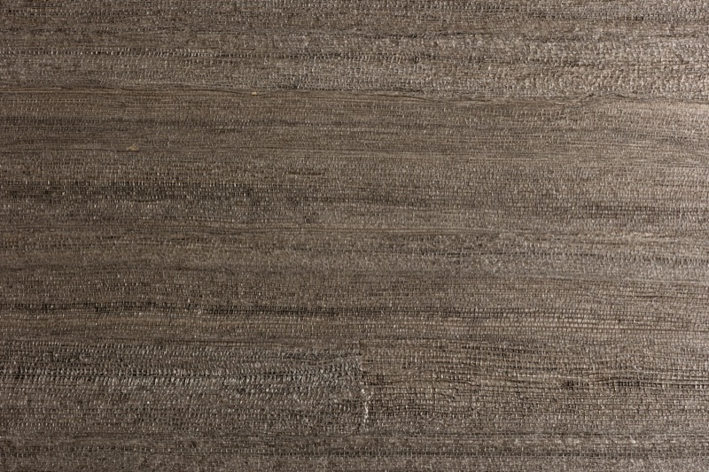 Close-up of dark brown grasscloth wallpaper showing tight horizontal reed weave in warm charcoal-brown with faint silver-grey filament flecks