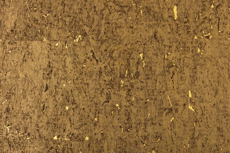 Close-up of Ember Gold cork wallcovering showing deep amber-brown compressed-cell base with scattered bright gold foil flecks