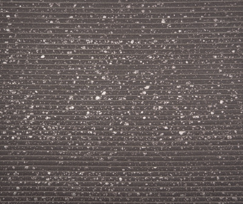 Крупный план образца Charcoal Frost — чёрные травяные обои из джута, тонкое горизонтальное рёберное плетение и рассеянные белые минеральные вкрапления на тёмно-угольном фоне