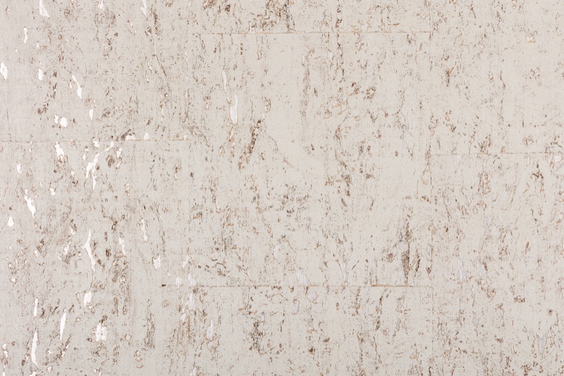 Close-up of Pearl Cork white cork wallcovering showing irregular cellular structure with warm tan fissures and scattered pearlescent highlights on an off-white cream surface